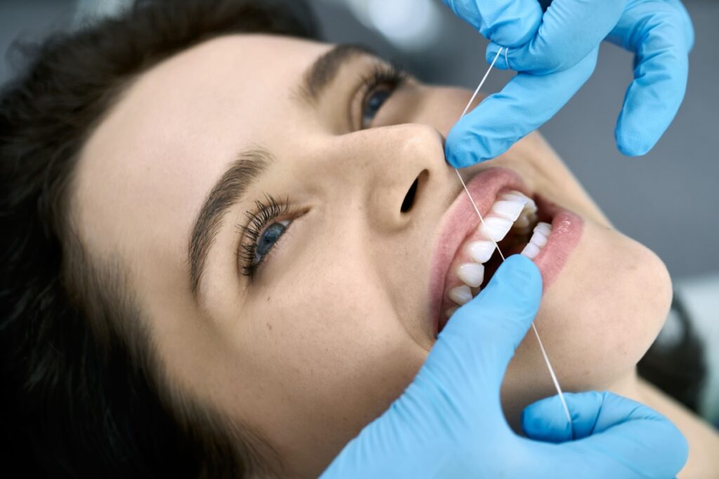 A person laying in a dental chair and getting their teeth flossed